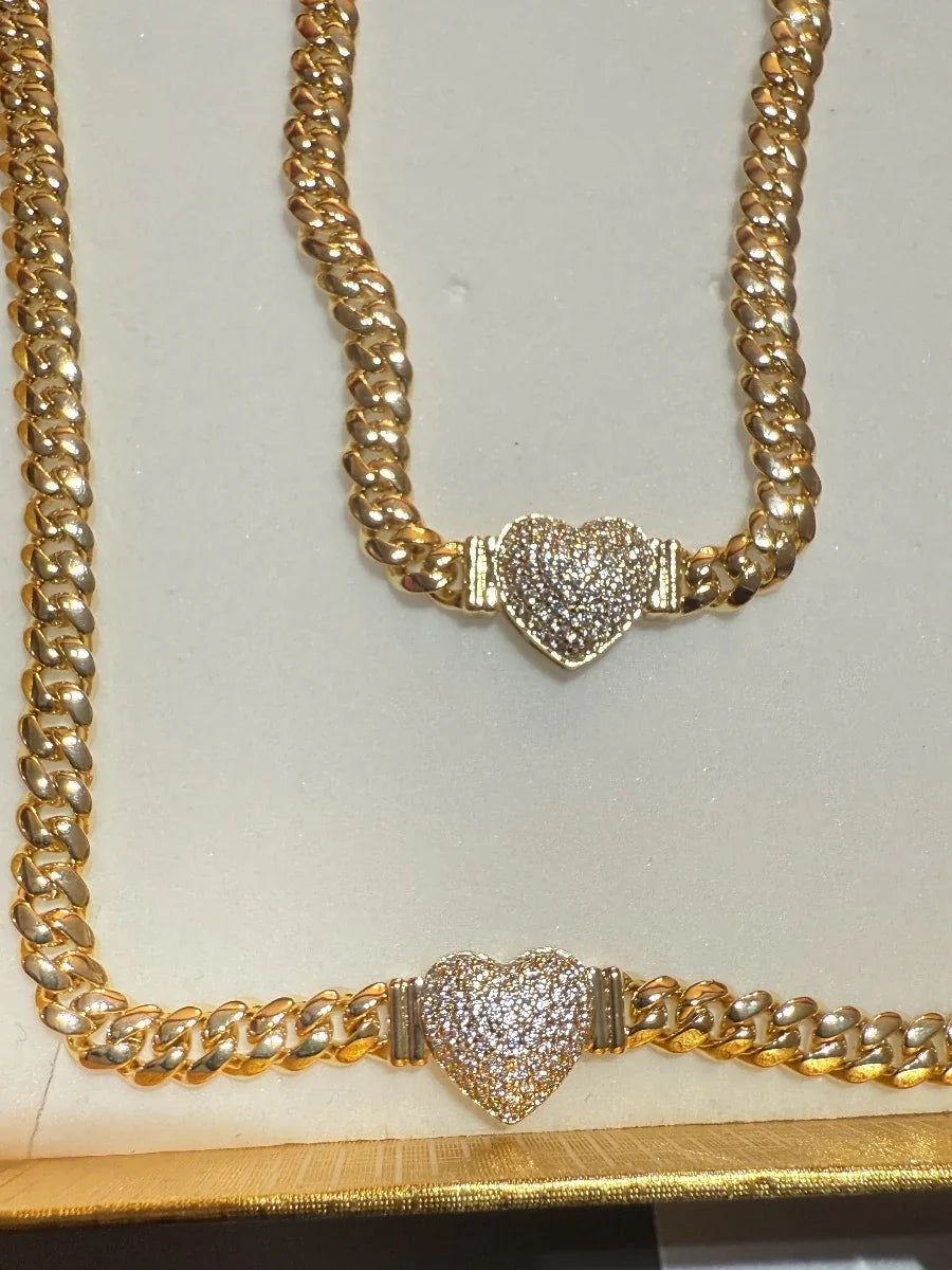 Conjunto de collar y pulsera de cadena gruesa dorada con dijes de corazón brillantes.