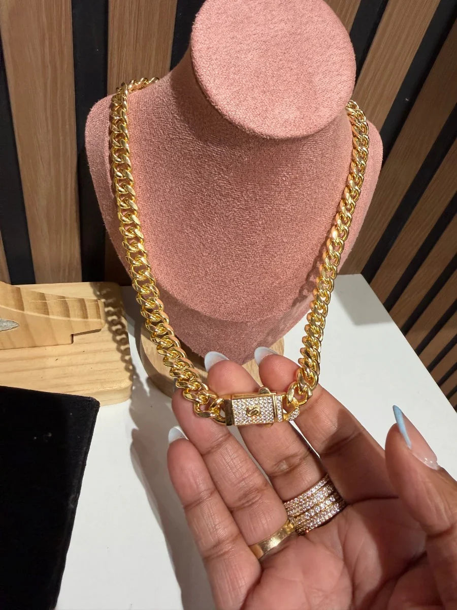 Cadena gruesa de eslabones dorados con broche decorativo, exhibida en busto de joyería