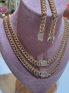 Juego de cadenas y pulsera tipo cubana doradas con broche de brillantes sobre exhibidor