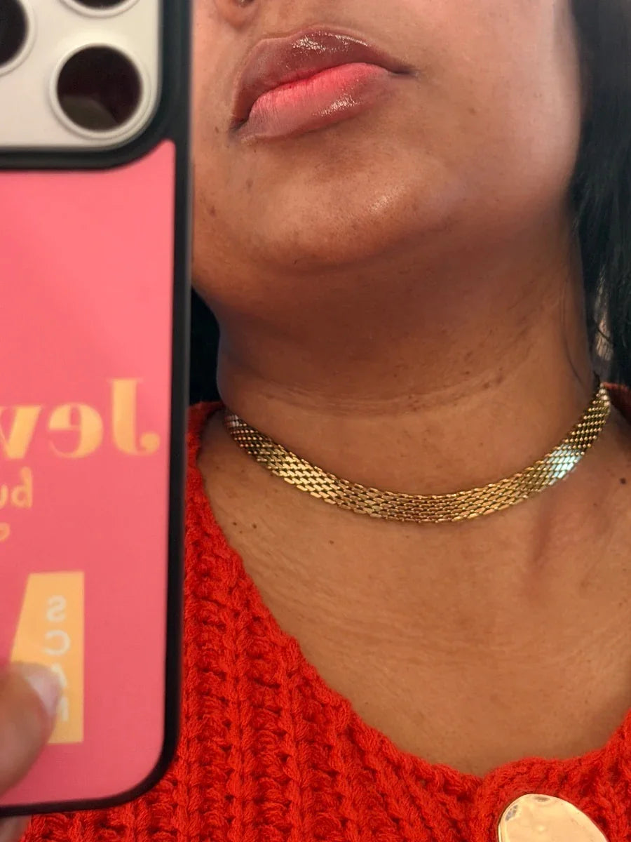 Mujer usando gargantilla dorada tejida, selfie parcial con suéter rojo