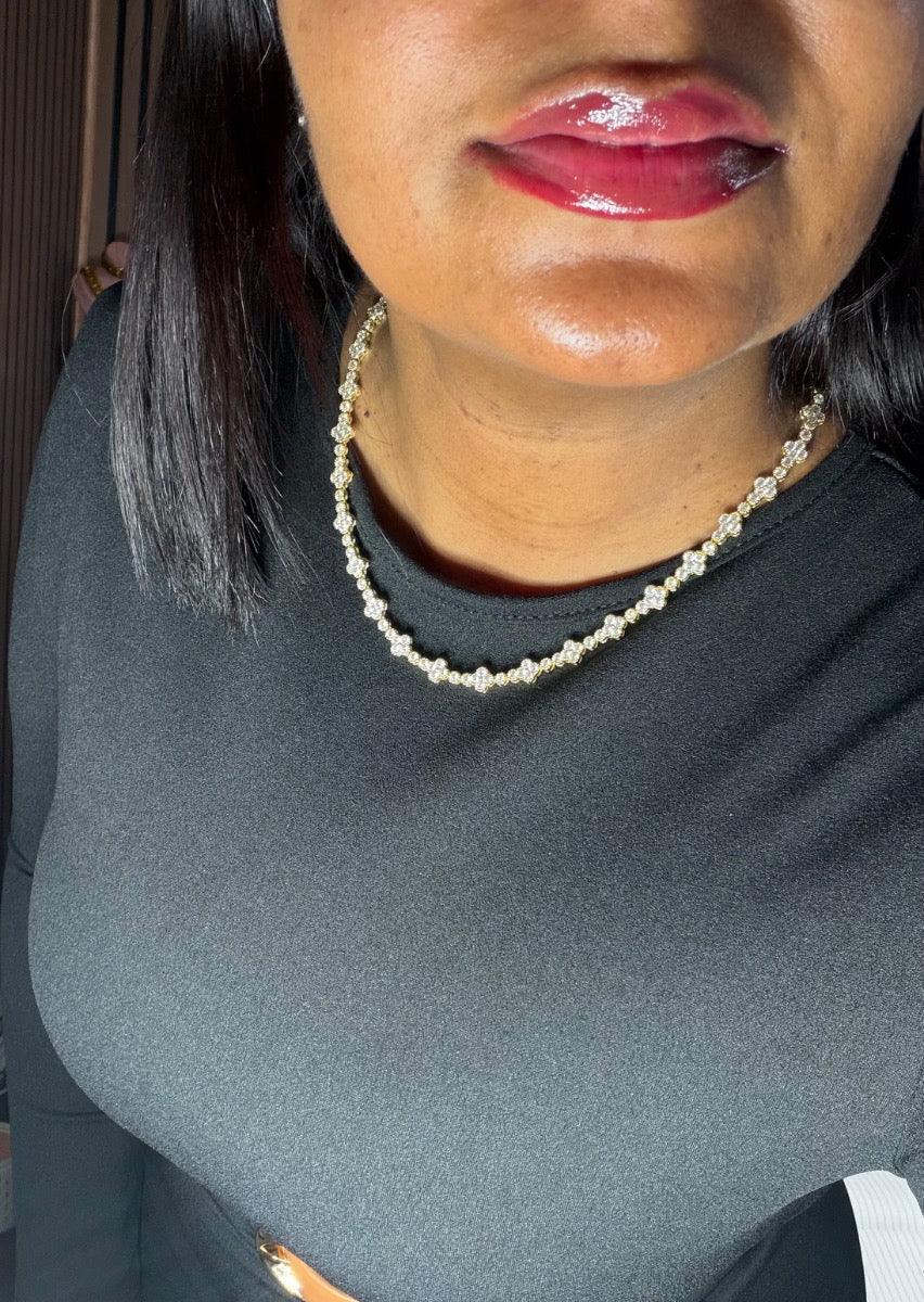 Mujer con collar de piedras brillantes, blusa negra elegante, labios maquillados