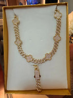 Set de collar y pulsera dorados con tréboles incrustados de circonias, exhibidos en estuche.