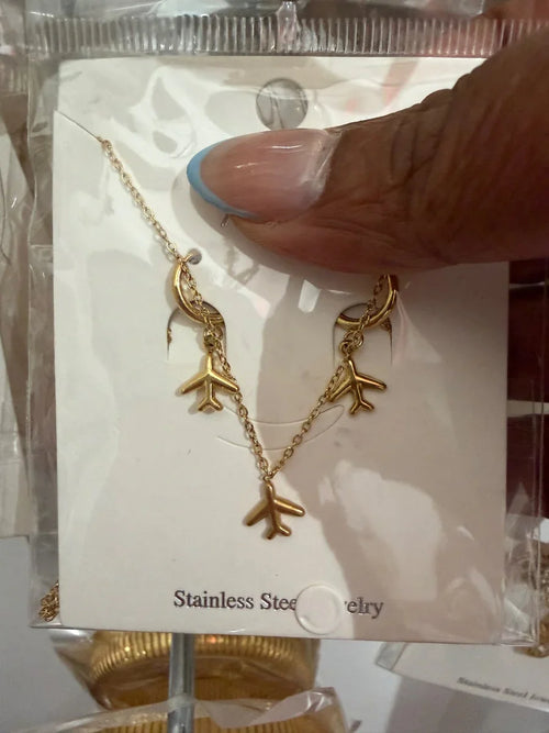 Collar de acero inoxidable con dijes dorados en forma de avión, fondo neutro