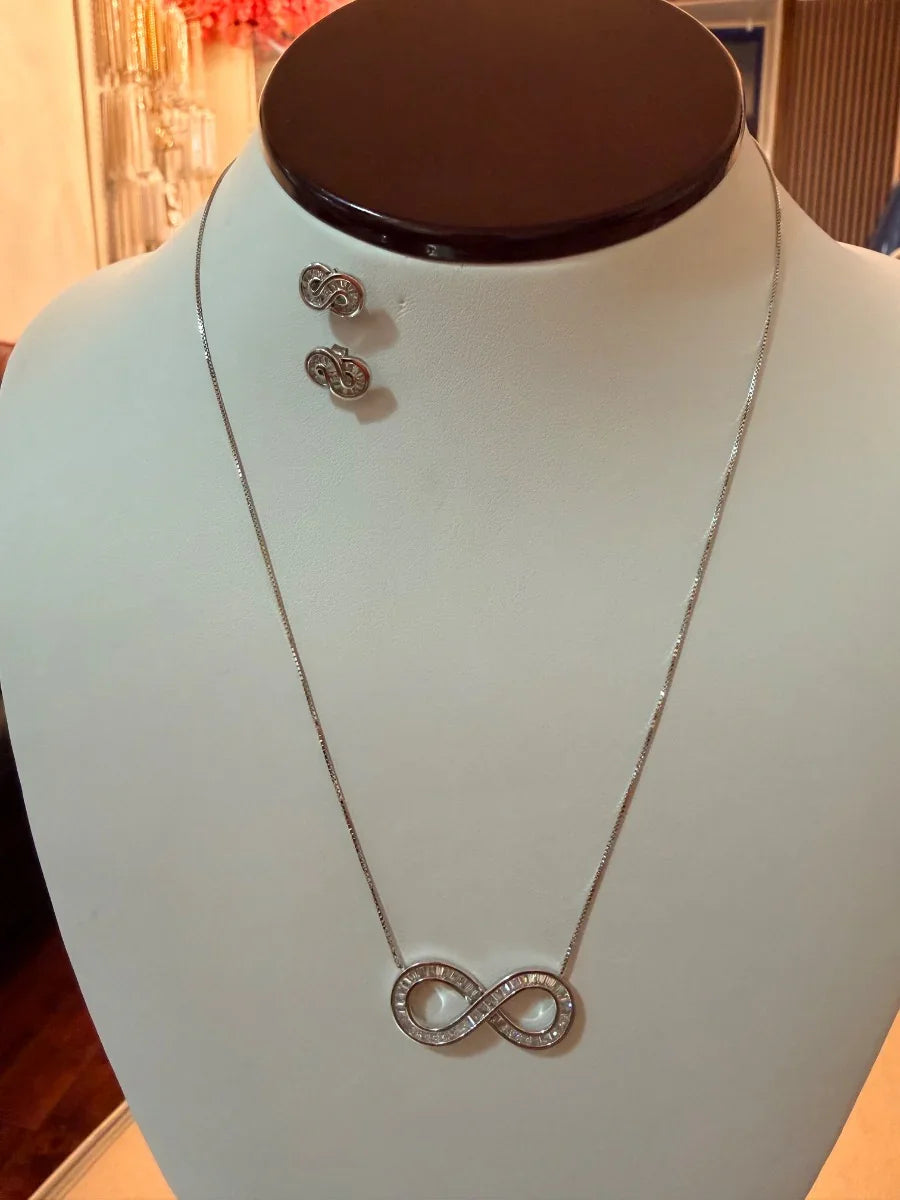 Set de collar y aretes de plata con símbolo infinito y circonias, exhibido en busto.