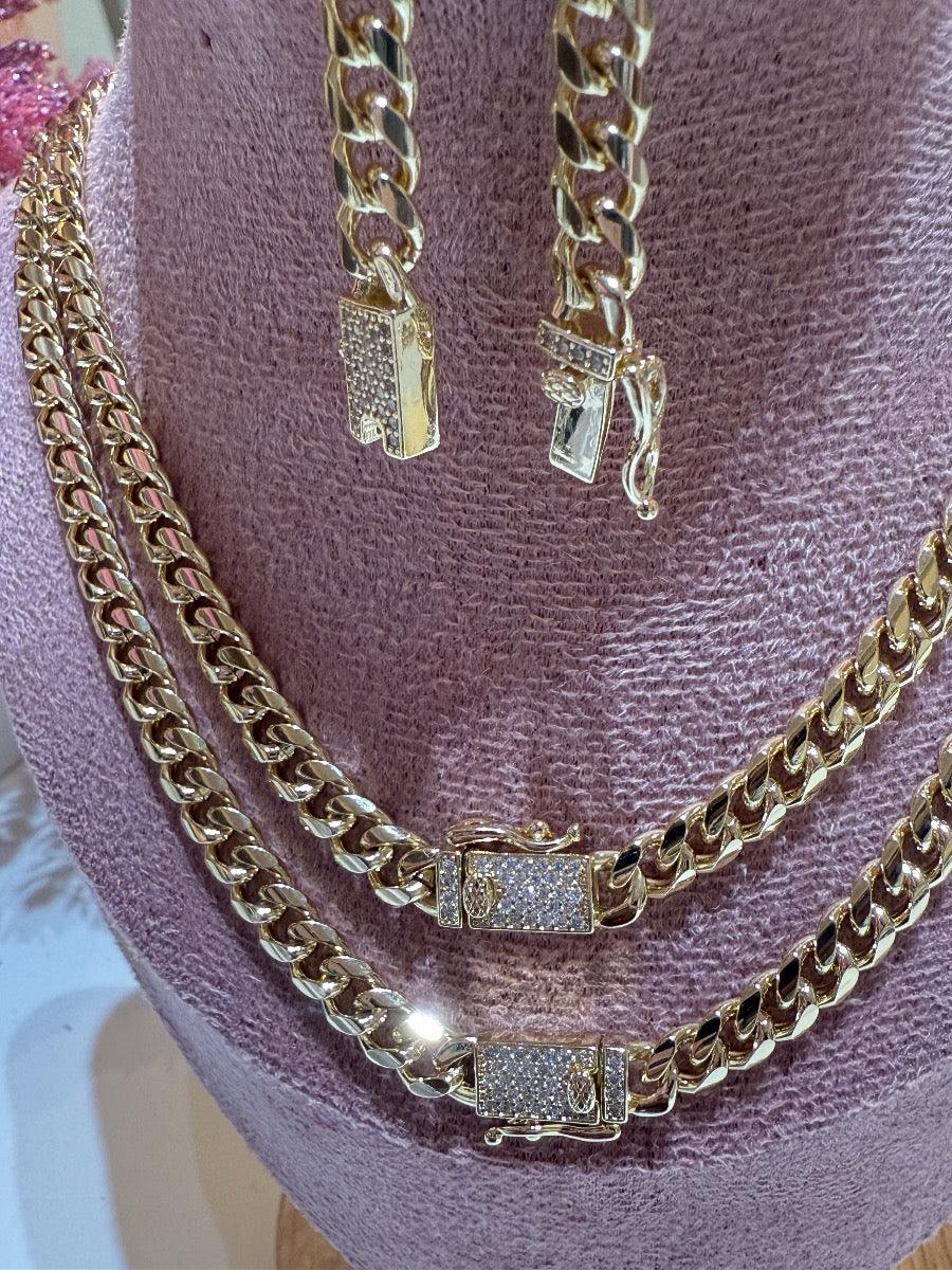 Juego de cadena y pulsera tipo cubana dorada con broches decorados con circonias sobre busto lila
