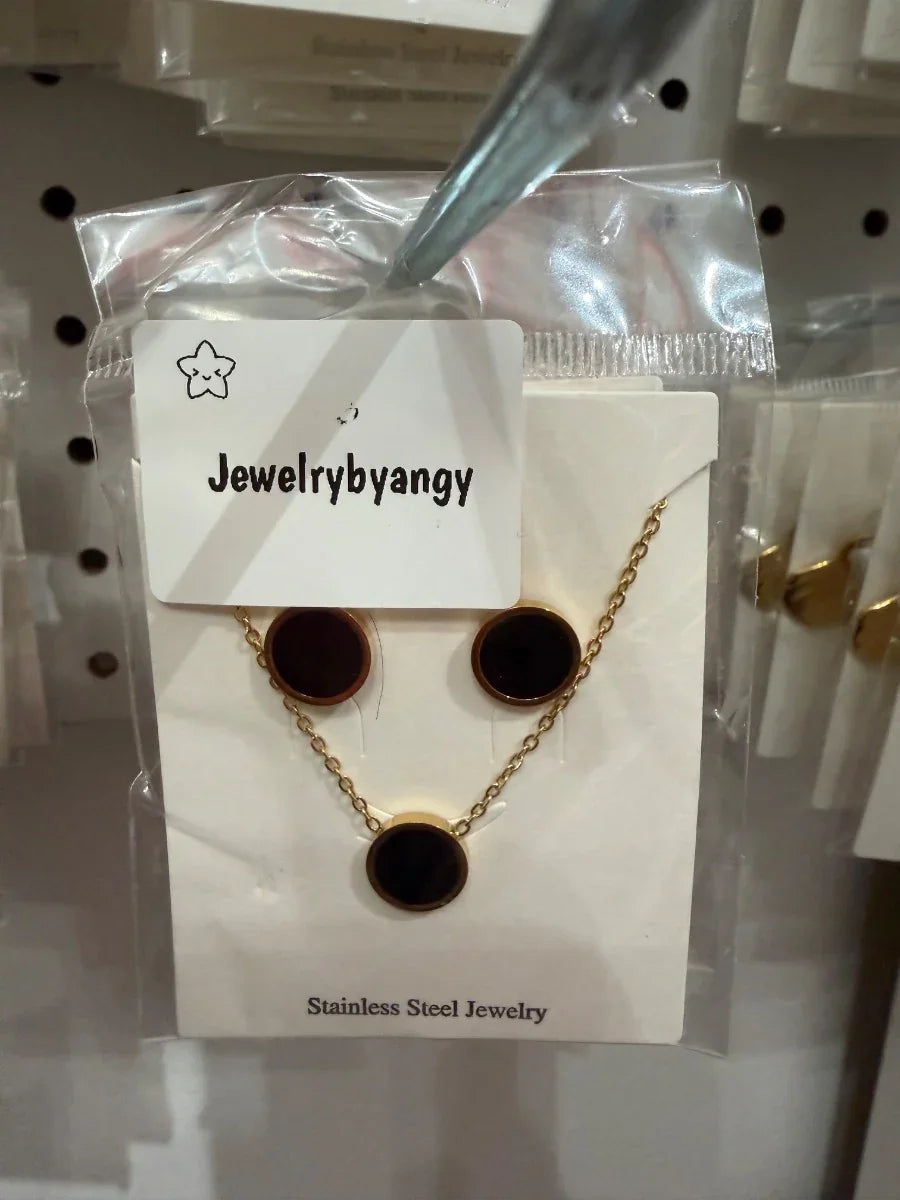 Set de joyería de acero inoxidable dorado con círculo negro, collar y aretes elegantes.