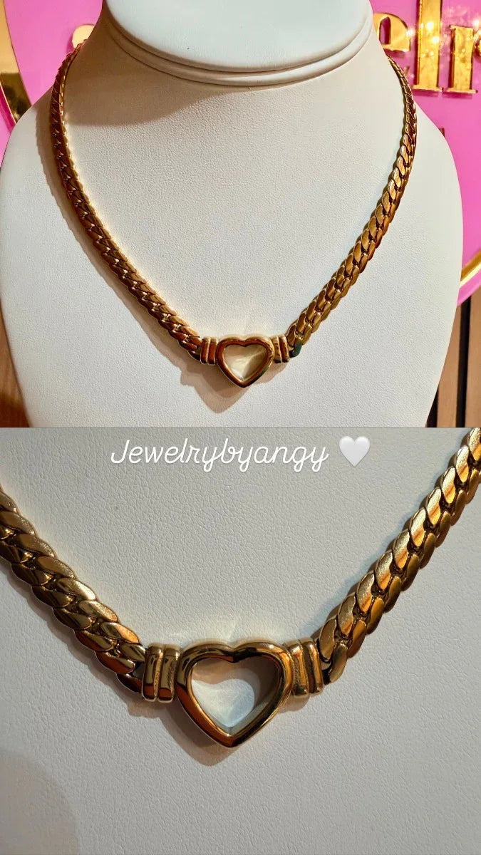 Collar de oro para mujer con eslabones gruesos y dije de corazón, exhibido en busto blanco.