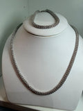 Set de collar y pulsera plateados con brillantes, exhibidos en busto blanco