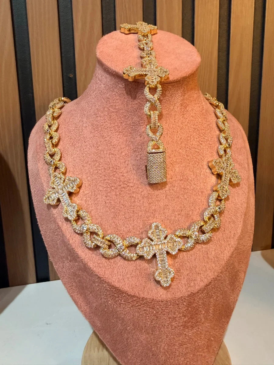Collar y pulsera dorados con cruces y diamantes, exhibidos en busto de joyería.