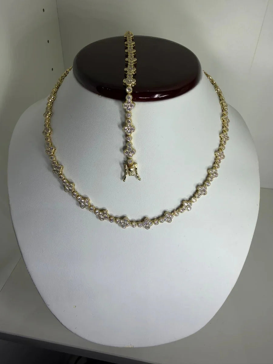 Conjunto de collar y pulsera dorados con incrustaciones de piedras brillantes, exhibidos en busto blanco.