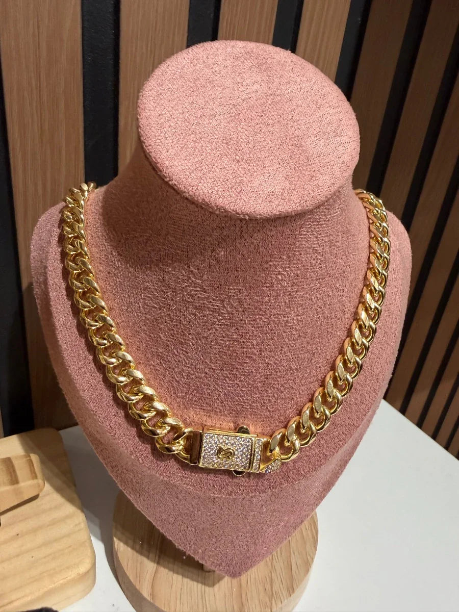 Collar cadena cubana dorada con broche de zirconias, exhibido en busto rosa, joyería elegante