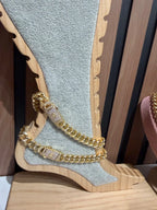 Tobillera de cadena gruesa dorada con broches brillantes sobre exhibidor de madera