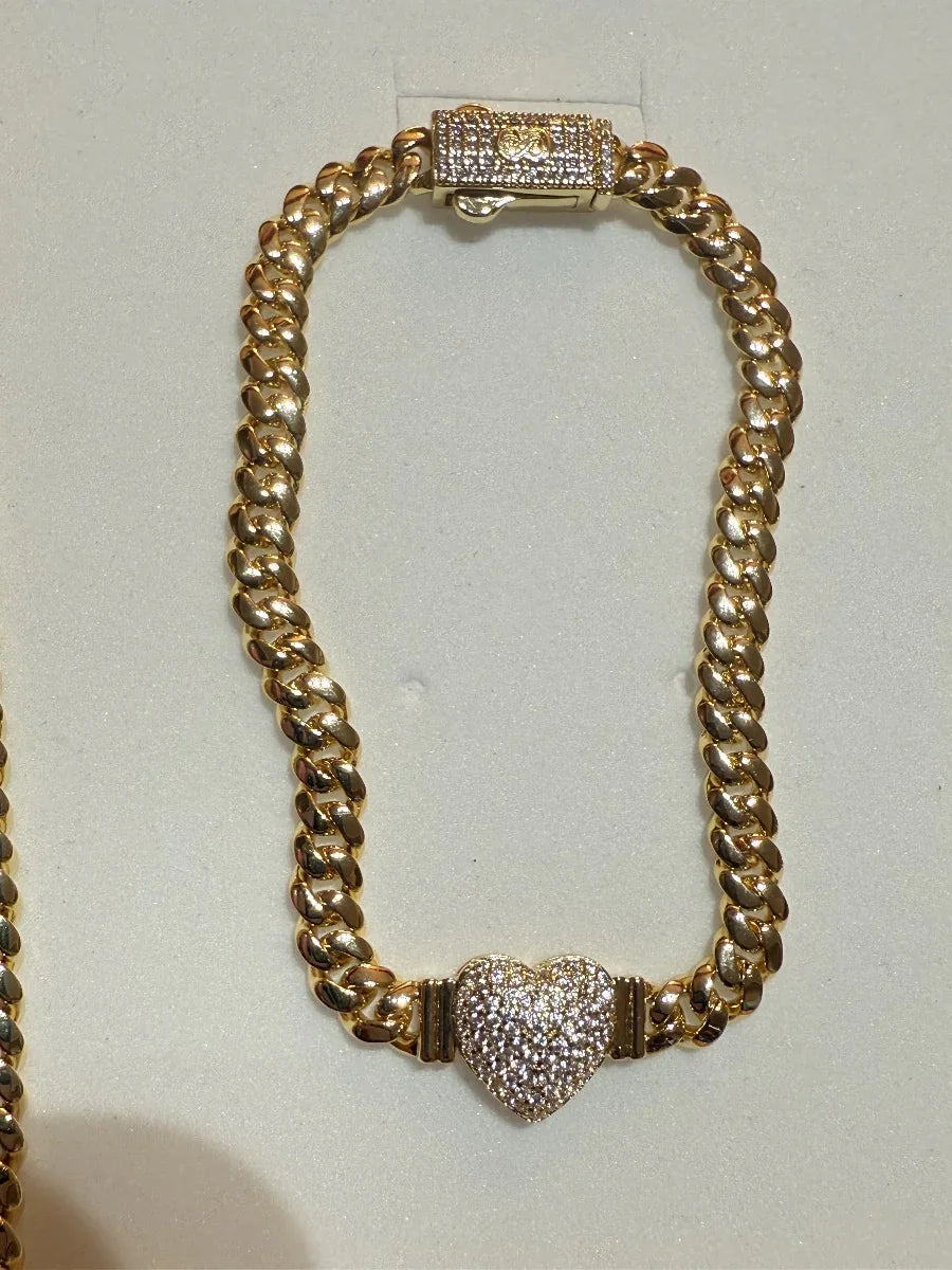 Pulsera de oro estilo cubano con dije de corazón de circonias brillantes, fondo beige
