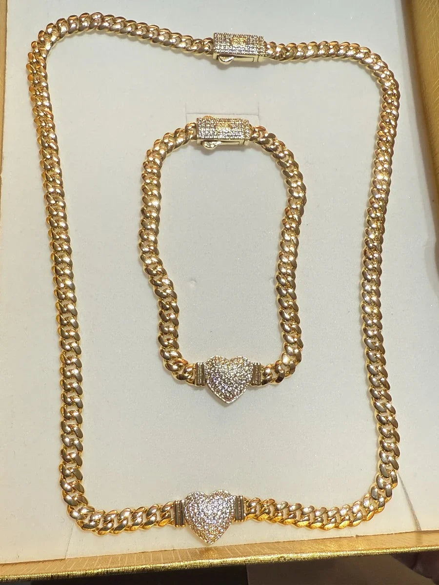 Conjunto de cadena y pulsera de oro con eslabones gruesos y corazones decorativos de zirconias.