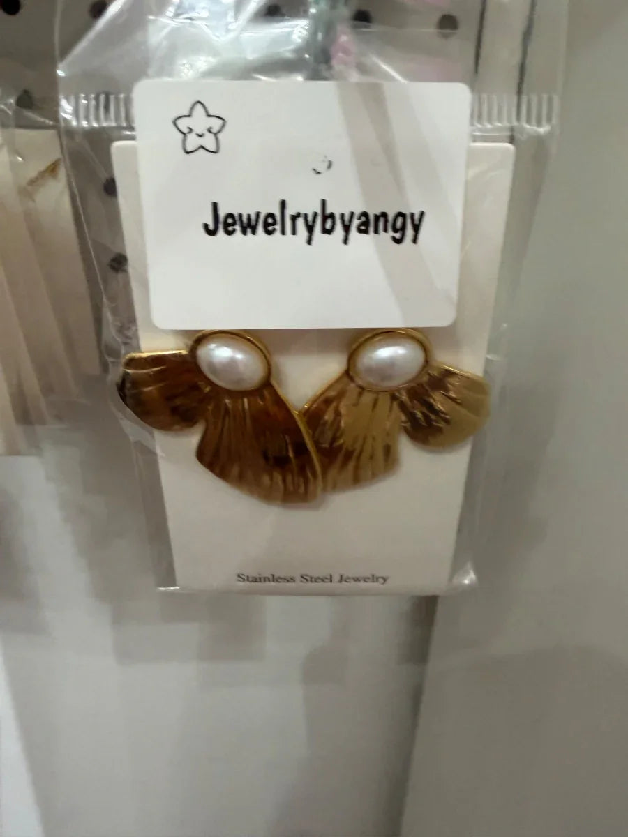 Aretes dorados de acero inoxidable con perlas decorativas sobre fondo blanco.