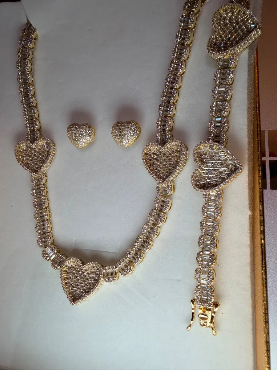 Juego de joyería dorada con corazones y circonias, incluye collar, pulsera y aretes.