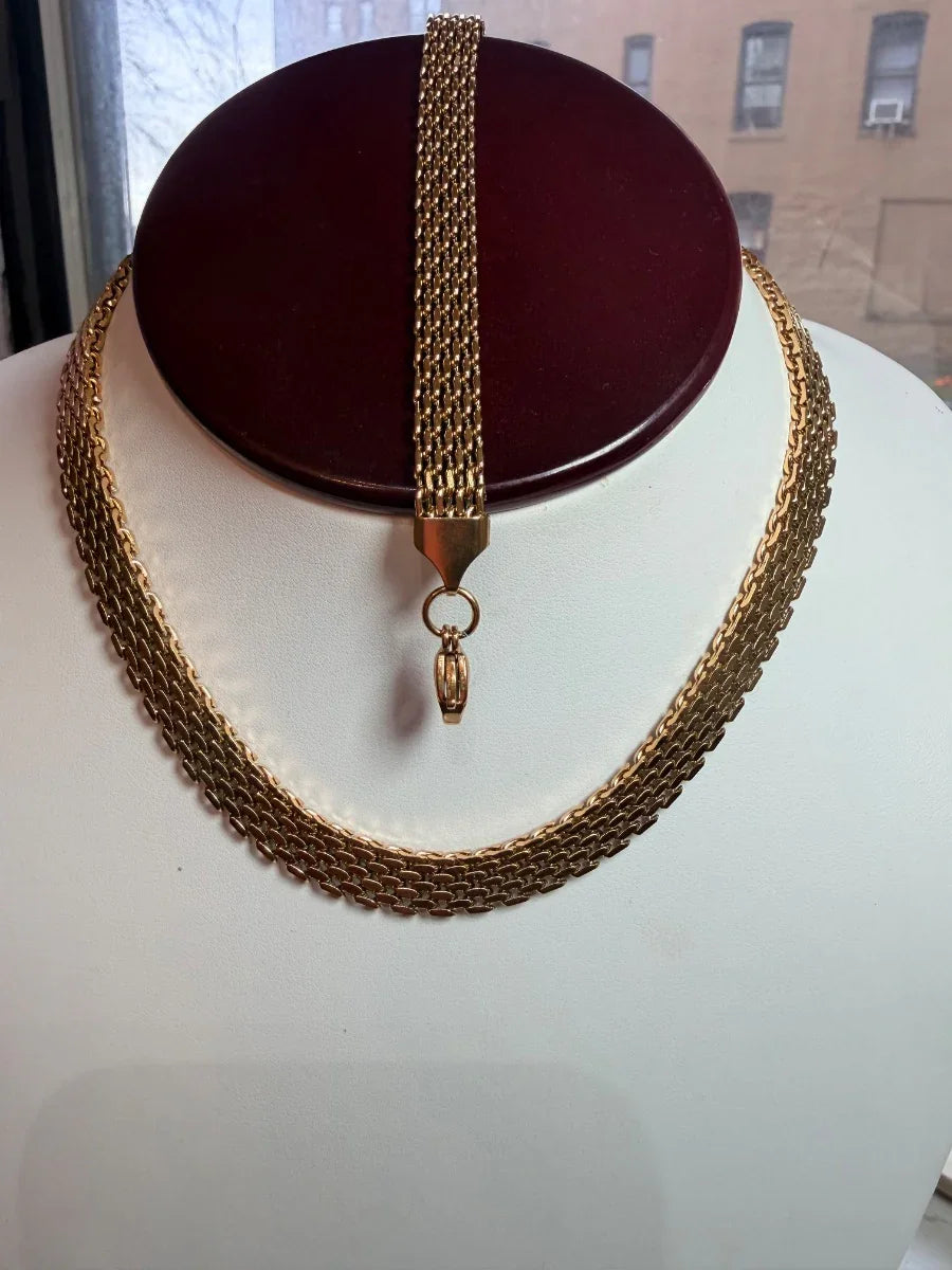 Set de collar y pulsera de oro amarillo tejido, exhibidos en busto para joyería elegante.