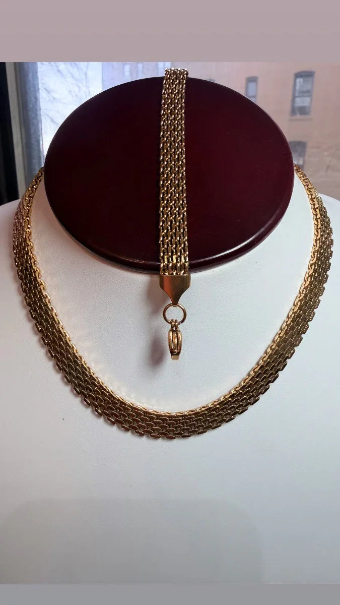Conjunto de collar y pulsera dorados de eslabones anchos sobre exhibidor en interior