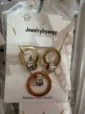 Conjunto de collar y aretes de acero inoxidable dorado con aros y detalles brillantes.