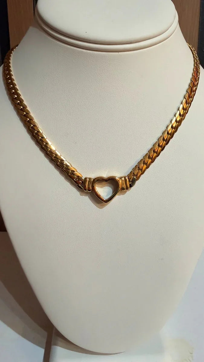 Collar de oro grueso con dije de corazón, expuesto en busto para joyería en vitrina